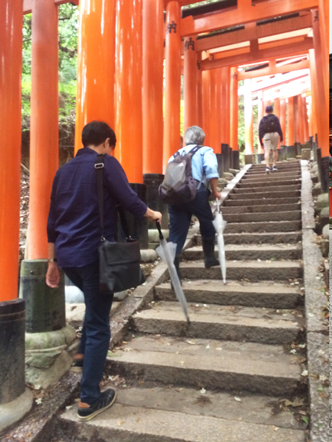 参道を傘を杖にして登る人々